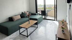 Una sala moderna con un sofá verde, una mesa de centro de madera y vistas a través de un gran ventanal corredero.