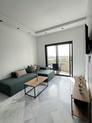 A modern living room with a green sofa, a wooden coffee table, and a view through a large sliding glass door. - Fabulous 1-bedroom studio perfect for a relaxing getaway (Unknown)