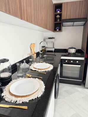 Een moderne keuken met een zwart aanrecht, witte kasten, een inbouwoven en een spoelbak.
