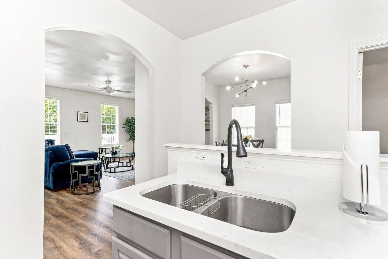 A modern kitchen with a stainless steel sink, a black faucet, and a white countertop.
