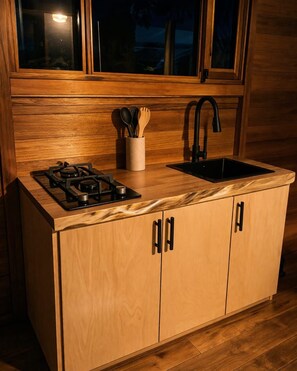 Una cocina compacta con estufa a gas, un lavamanos y armarios de madera.