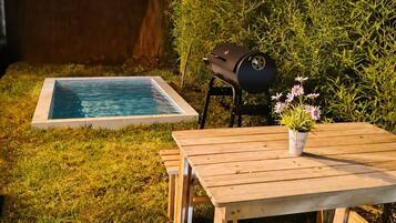 A pool with a wooden deck and a barbecue grill.