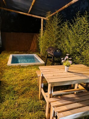 Piscina com deck de madeira e churrasqueira.