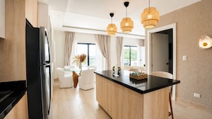 Een moderne keuken met een centraal eiland, een eethoek met een glazen tafel en hanglampen.