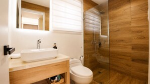 A modern bathroom with a wooden vanity, a white sink, and a glass-enclosed shower. - Luxury Rooftop with Views of Cana: Pool, Sunset, Golf (Punta Cana)
