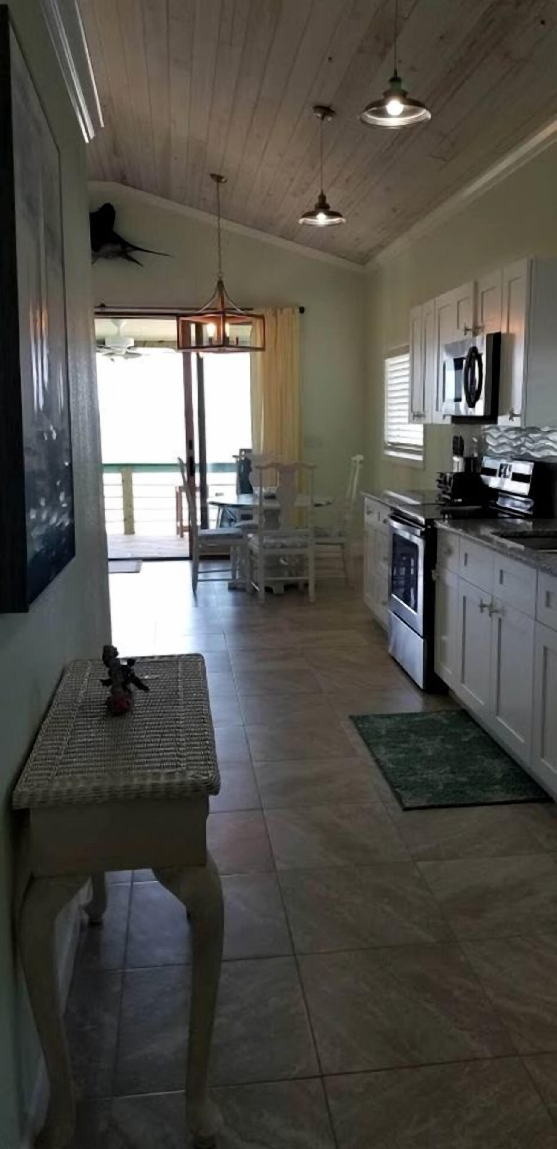 A kitchen with white cabinets, a microwave, and a dining area with chairs.