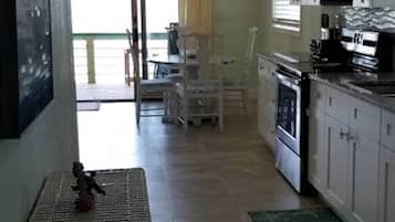 A kitchen with white cabinets, a microwave, and a dining area with chairs.