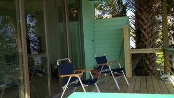A covered outdoor area with a ceiling fan, a wooden deck, and two chairs.