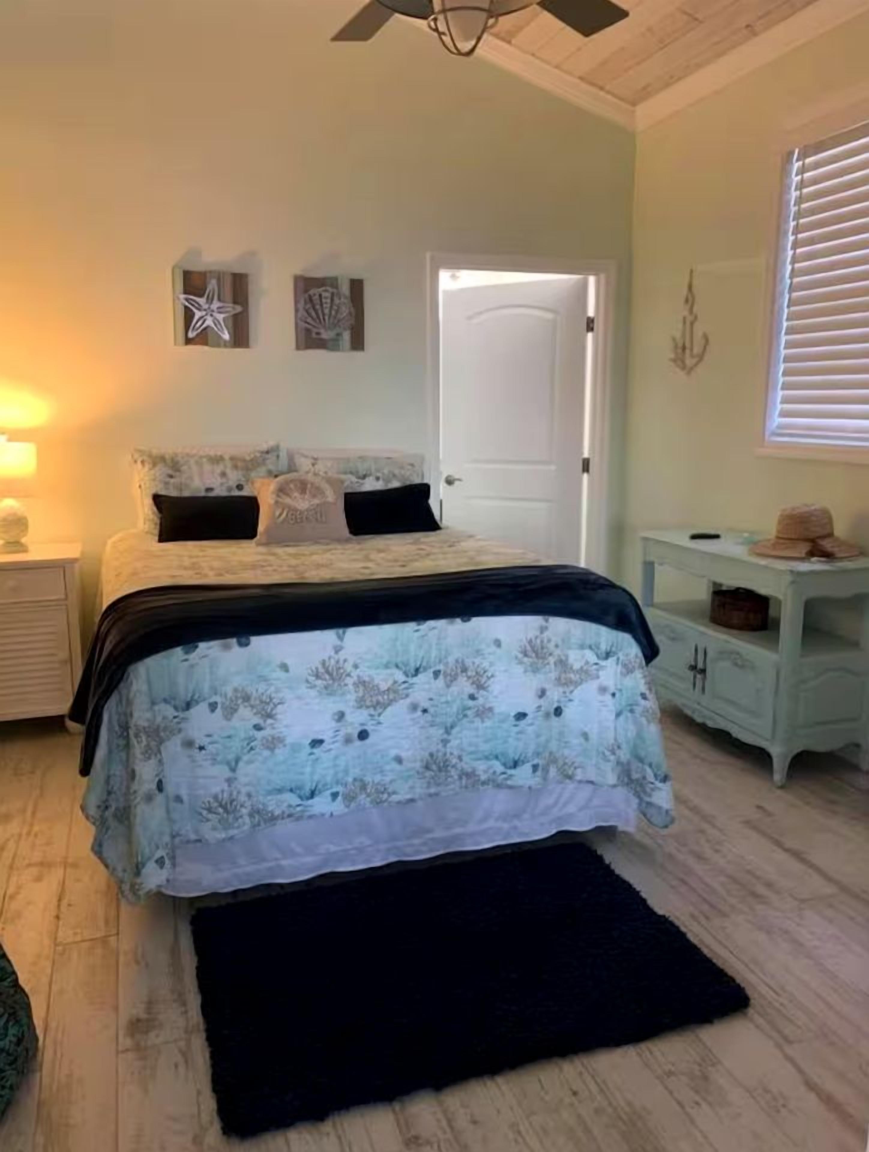 Une chambre à coucher avec un lit, une table de chevet, une commode et une porte.
