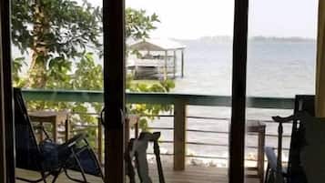 A room with a view of the sea, a table, and chairs.