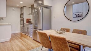 A modern kitchen with stainless steel appliances, a dining area with a wooden table and chairs, and a round mirror on the wall. - Superb 4-bedroom condo with AC in quaint Brian Head steps from Giant Steps Lodge (Brian Head)