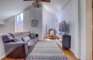 A living room with a sofa, armchair, television, and patterned rug.