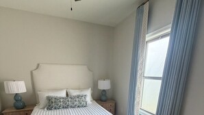 A bedroom with a large bed, two bedside tables with lamps, a ceiling fan, and a window with curtains. - Newly furnished getaway, minutes from Ole Miss! (Oxford)