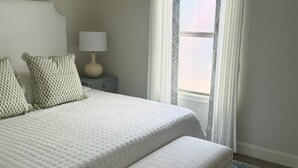 A bedroom with a large bed, a bedside table with a lamp, and a window with curtains. - Newly furnished getaway, minutes from Ole Miss! (Oxford)