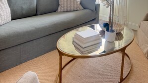 A living room with a grey sofa, a round glass coffee table, and a potted plant. - Newly furnished getaway, minutes from Ole Miss! (Oxford)
