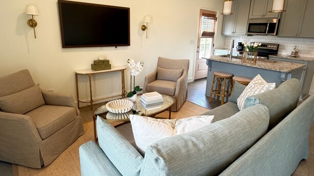 A modern living room with a grey sofa, a coffee table, and a TV mounted on the wall. - Newly furnished getaway, minutes from Ole Miss! (Oxford)