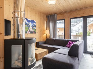 Ett mysigt vardagsrum med en öppen spis, en soffa, ett soffbord och en tavla på väggen.