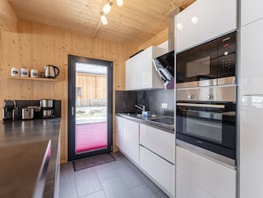 Eine moderne Küche mit Holzwänden, Edelstahlgeräten und einer schwarzen Arbeitsplatte.