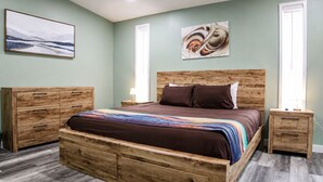 Una camera da letto con un letto in legno, comodini, una cassettiera e opere d'arte alle pareti.