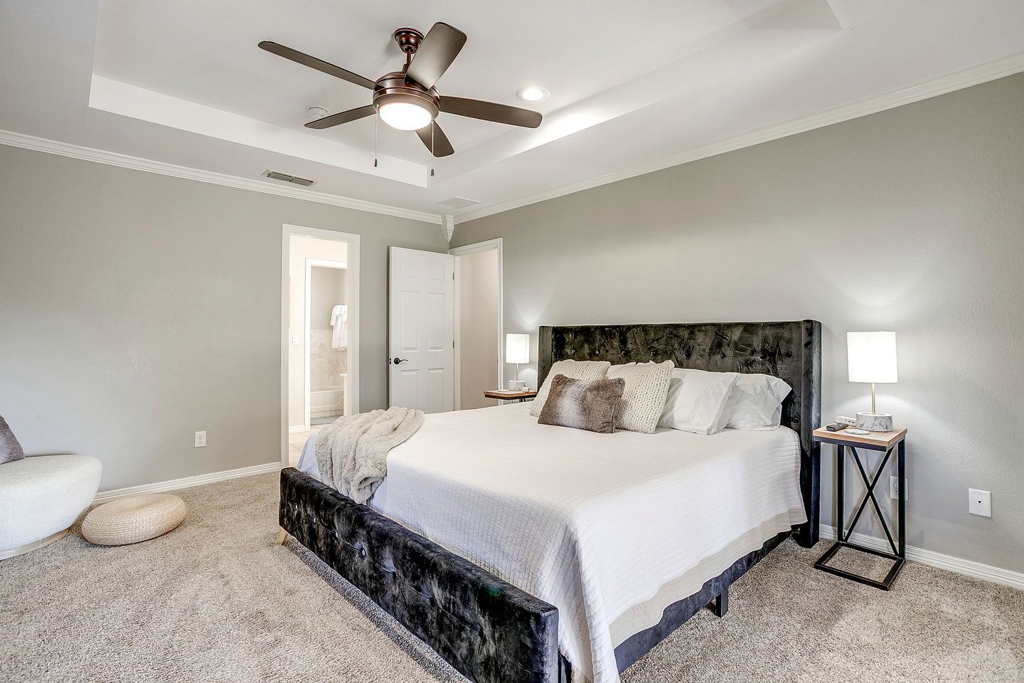 A bedroom with a bed, a ceiling fan, a nightstand, and a lamp.