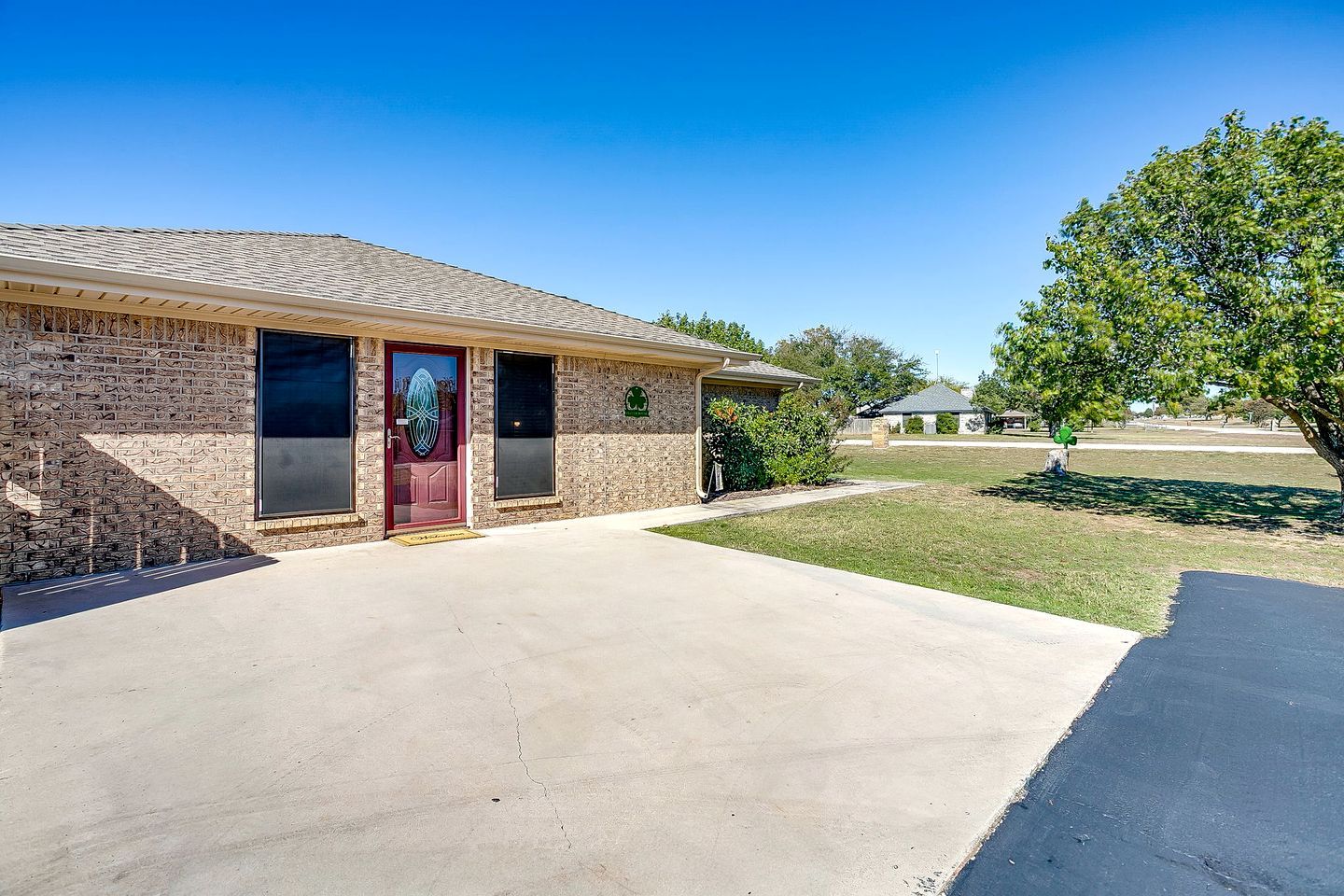 A single-story building with a brick facade, a red door, and a clear sky.