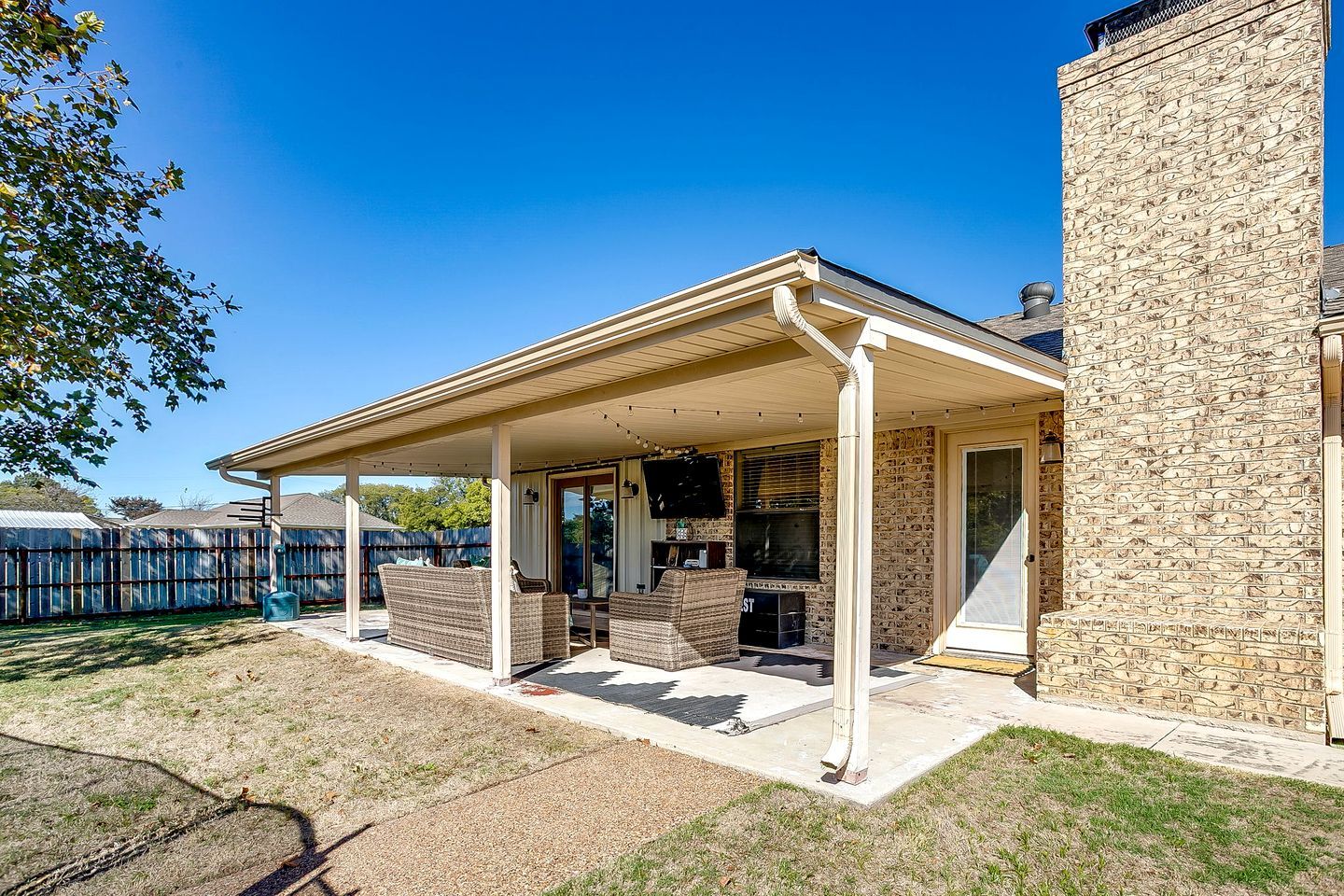 Un patio couvert, aménagé avec du mobilier d’extérieur, et un bâtiment en pierre.