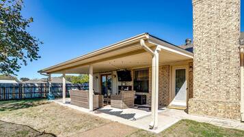 Un patio couvert, aménagé avec du mobilier d’extérieur, et un bâtiment en pierre.