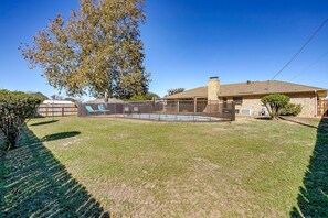 A backyard with a swimming pool, a covered patio, and a house with a brick exterior. - Comfortable Pool Home with Spacious Game Room Escape in Decatur, Texas (Decatur)