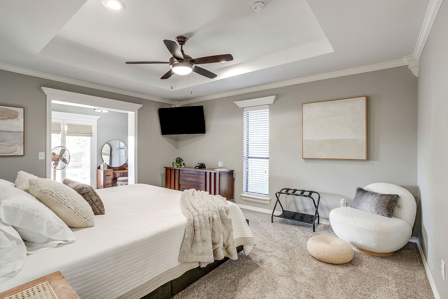 Une chambre à coucher comprenant un lit, un ventilateur de plafond, une télévision, une commode, une chaise et une fenêtre.