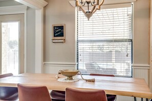 A dining area with a wooden table, chairs, a chandelier, and a window with blinds. - Comfortable Pool Home with Spacious Game Room Escape in Decatur, Texas (Decatur)