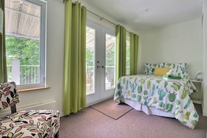 A bedroom with a bed, a chair, and a window with curtains.
