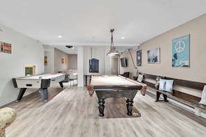 A pool table in a room with a billiards table, a bench, and a wall with a peace sign poster.