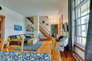 Una sala de estar acogedora con un sofá, sillones, una mesa de centro y una escalera que sube a otra habitación.