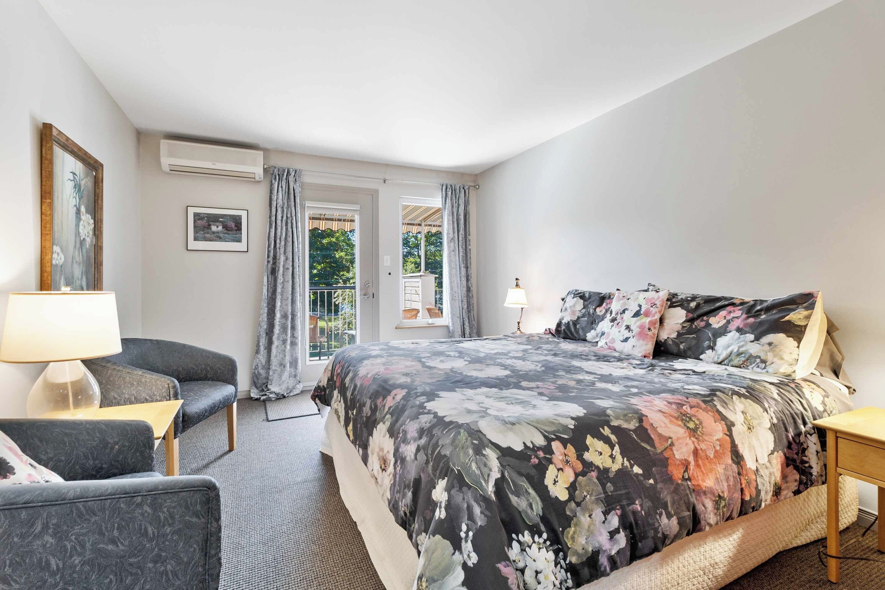 Une chambre à coucher avec un lit, une chaise, une lampe et une fenêtre avec des rideaux.