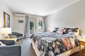 A bedroom with a bed, a chair, a lamp, and a window with curtains.