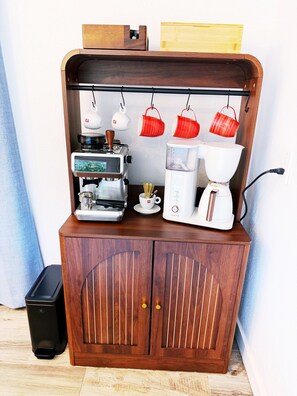 Un armari de fusta amb una màquina de cafè, una balança i tasses vermelles penjades.