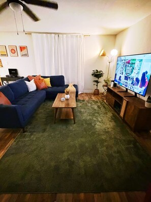 A living room with a sectional sofa, a coffee table, a television, and a ceiling fan. - Spacious 4-bedroom house in lovely Denton TX (Denton)
