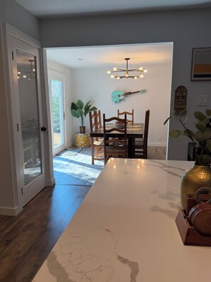 A dining area with a marble countertop, wooden chairs, a guitar wall art, and a potted plant. - Spacious 4-bedroom house in lovely Denton TX (Denton)