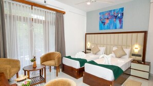 Hotellihuone, jossa on kaksi sänkyä, työpöytä, tuoli, pieni pöytä ja kattotuuletin.