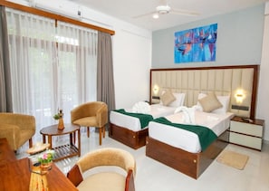 A hotel room with two beds, a desk, a chair, a small table, and a ceiling fan. - Hotel Vishwa Retreat - Kandy (Kandy)