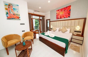 A hotel room with a large bed, two armchairs, a small table, and artwork on the walls. - Hotel Vishwa Retreat - Kandy (Kandy)