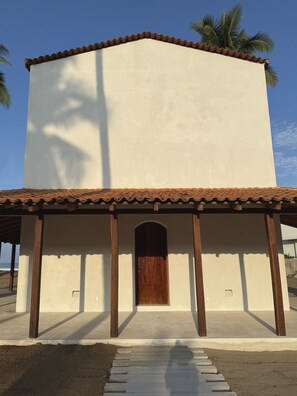 A building with a white facade, a brown tiled roof, and a wooden door. - Casa Apsara: 3-Bedroom Beachfront Villa on Rare Coastline (Zihuatanejo)
