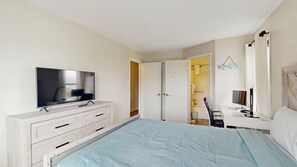 Ein Schlafzimmer mit Bett, Fernseher, Schreibtisch und Kleiderschrank.