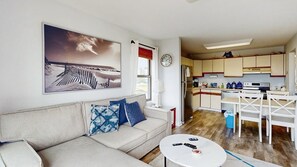 Ein Wohnzimmer mit einer Couch, einem Couchtisch und einem Bild von einer Strandansicht.