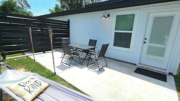 Un patio exterior con una mesa, sillas, una hamaca y una valla de madera.