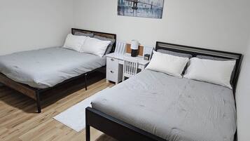 Une chambre avec deux lits, une table de chevet, une lampe et un tableau au mur.