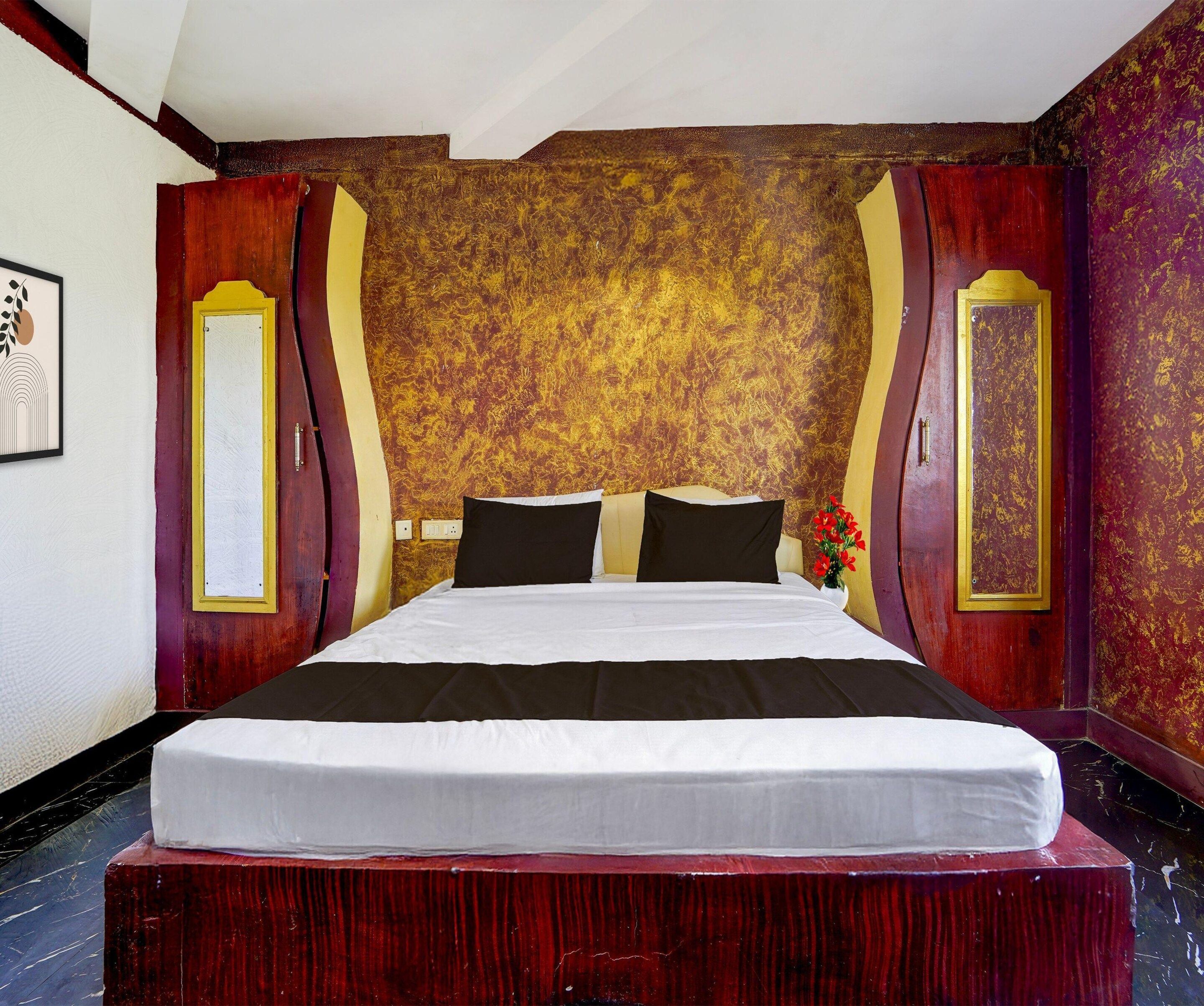 A hotel room with a large bed, a wooden headboard, and a decorative wall with a golden pattern.