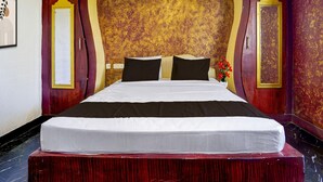 Habitación de hotel con una cama grande, un cabecero de madera y una pared decorativa con un motivo dorado.