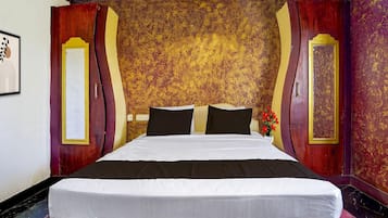 A hotel room with a large bed, a wooden headboard, and a decorative wall with a golden pattern.