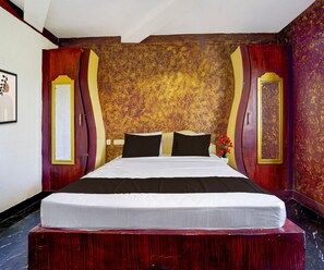 Quarto de hotel com uma cama grande, cabeceira de madeira e parede decorativa com padrão dourado.